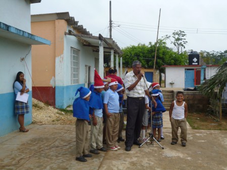 director haciendo la presentacion  de un grupo  de niños cantando un villancico